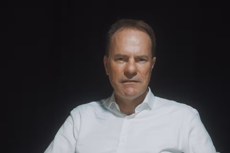 Stephan Keller sitzt in einem Sessel vor einem schwarzen Hintergrund